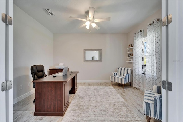 office featuring ceiling fan, light wood-type flooring, visible vents, and baseboards