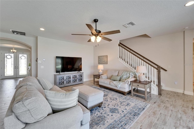 living room featuring stairs, visible vents, arched walkways, and french doors