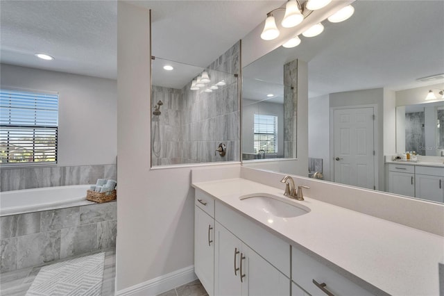 bathroom featuring a healthy amount of sunlight, a garden tub, vanity, and walk in shower