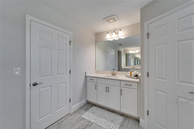 bathroom with baseboards, visible vents, and vanity