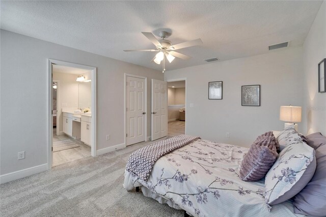 bedroom featuring light carpet, a textured ceiling, visible vents, and baseboards