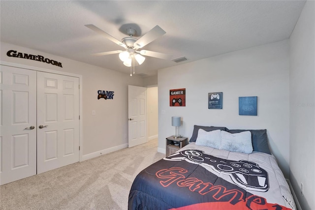 bedroom featuring a closet, visible vents, light carpet, ceiling fan, and a textured ceiling