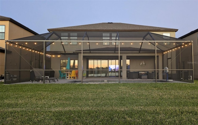 rear view of house with a yard, a lanai, a patio, and stucco siding