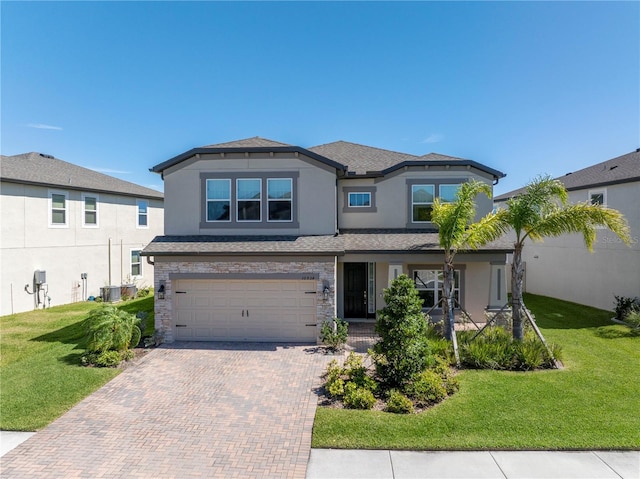 view of front of house featuring an attached garage, stone siding, decorative driveway, stucco siding, and a front yard