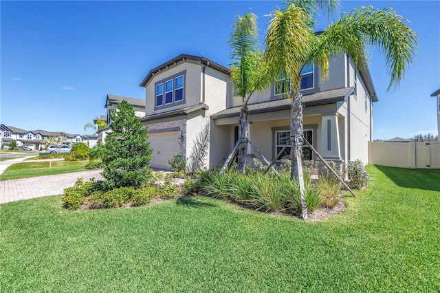 view of front of house with stucco siding, an attached garage, fence, decorative driveway, and a front yard