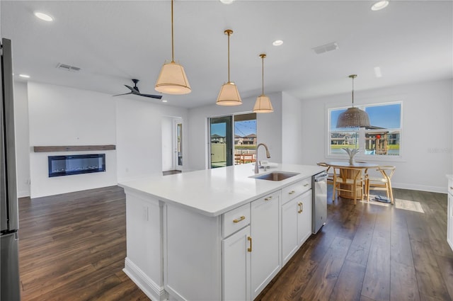 kitchen with dark wood-type flooring, a sink, visible vents, stainless steel dishwasher, and a glass covered fireplace