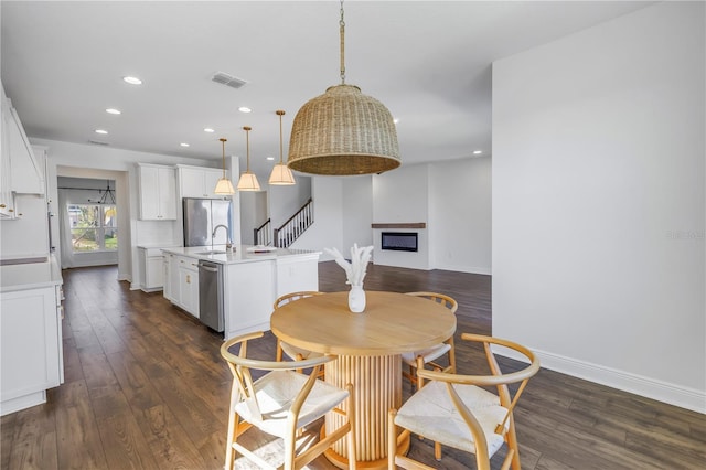 dining space with dark wood-type flooring, a fireplace, visible vents, and baseboards