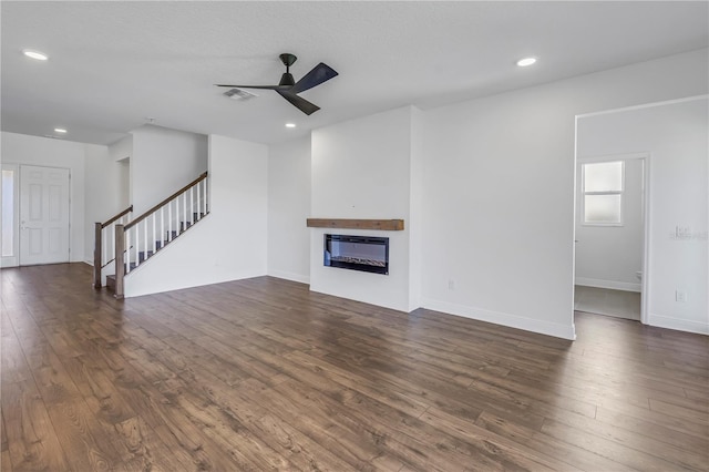 unfurnished living room featuring dark wood-style floors, a glass covered fireplace, and visible vents