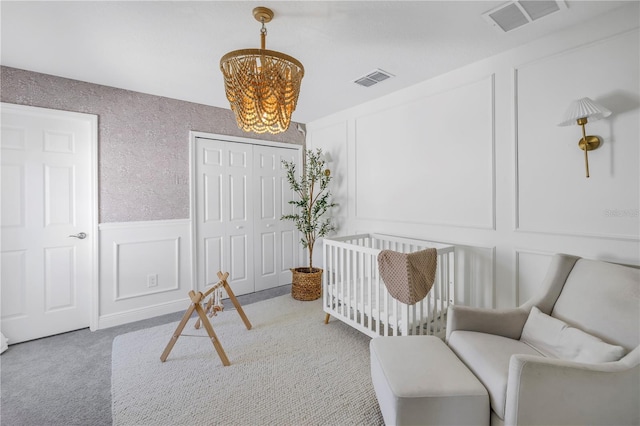 carpeted bedroom featuring a closet, an inviting chandelier, visible vents, and a decorative wall