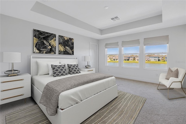 carpeted bedroom featuring a raised ceiling, visible vents, and baseboards