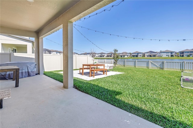 view of yard with a water view, a fenced backyard, a residential view, and a patio