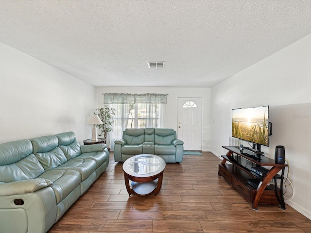 living room with visible vents, a textured ceiling, and wood finish floors