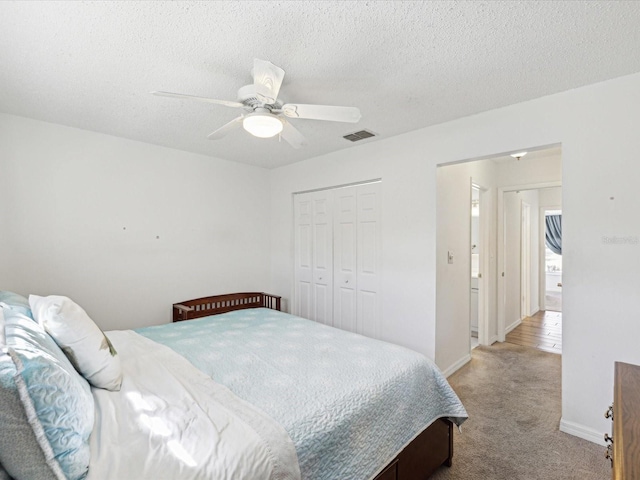 bedroom with light colored carpet, visible vents, a closet, and a textured ceiling