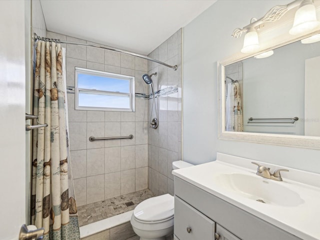 bathroom featuring tiled shower, toilet, and vanity