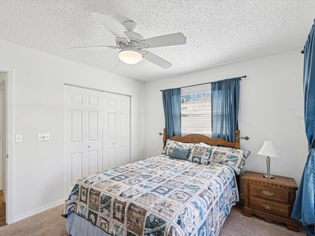 carpeted bedroom with a closet, baseboards, a textured ceiling, and a ceiling fan