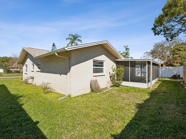 rear view of property with stucco siding, a lawn, fence, and a sunroom