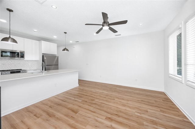 3402 E 28th Ave Unit 7, Tampa, FL 33605 - kitchen with appliances with stainless steel finishes, decorative backsplash, white cabinetry, light countertops, and light wood-style flooring