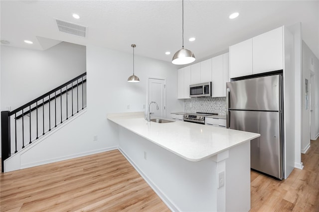 3402 E 28th Ave Unit 7, Tampa, FL 33605 - kitchen featuring appliances with stainless steel finishes, a sink, light wood finished floors, decorative backsplash, and white cabinetry