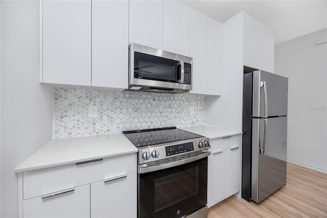 3402 E 28th Ave Unit 7, Tampa, FL 33605 - kitchen featuring stainless steel appliances, light wood-style flooring, light countertops, white cabinetry, and tasteful backsplash