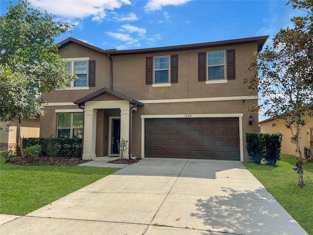 traditional home with a garage, concrete driveway, a front lawn, and stucco siding