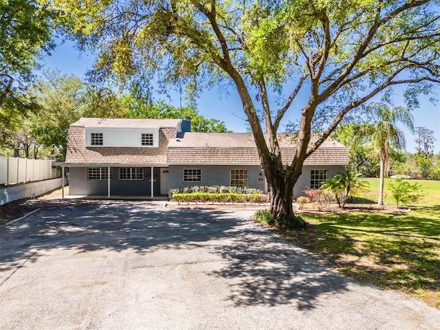 view of front of home featuring roof with shingles, a front lawn, and fence