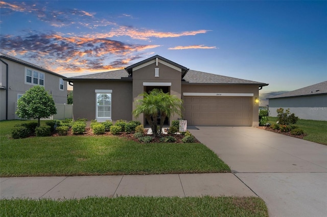 view of front of house with stucco siding, driveway, a front lawn, and an attached garage