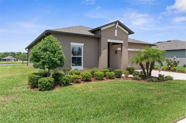 view of front of home featuring an attached garage, stucco siding, a front lawn, a shingled roof, and driveway