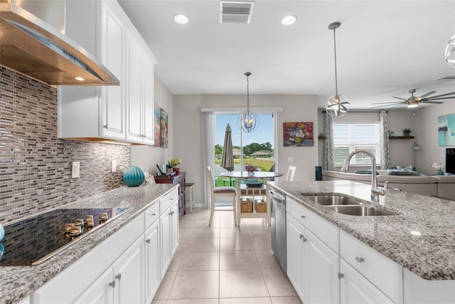 kitchen featuring a sink, wall chimney range hood, black electric stovetop, stainless steel dishwasher, and white cabinetry