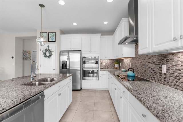 kitchen featuring appliances with stainless steel finishes, a sink, wall chimney range hood, backsplash, and recessed lighting