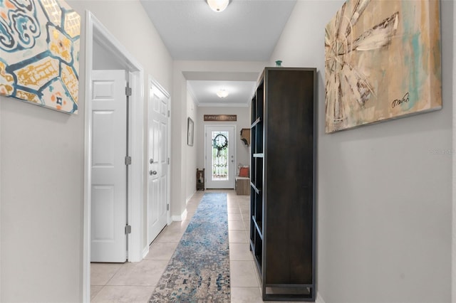hall featuring ornamental molding, light tile patterned floors, and baseboards