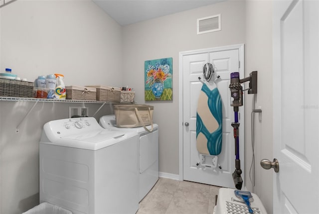 laundry area with independent washer and dryer, light tile patterned floors, and baseboards
