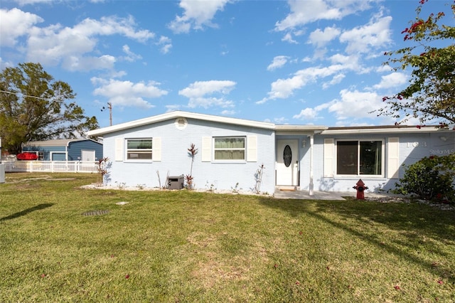 view of front of property with cooling unit, brick siding, a front yard, and fence