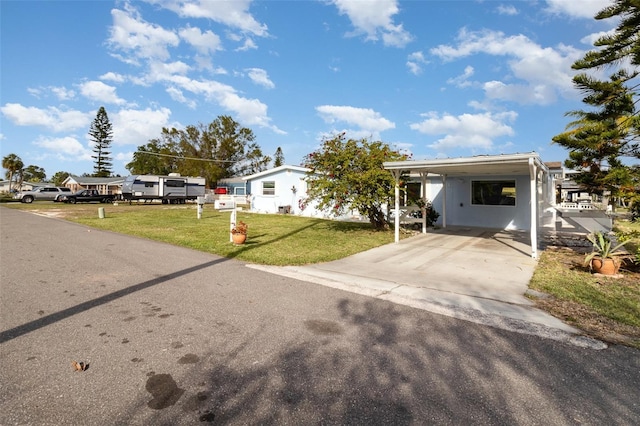 manufactured / mobile home featuring a carport, concrete driveway, and a front lawn