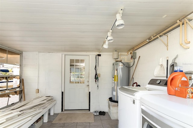 washroom featuring concrete block wall, electric water heater, washing machine and dryer, and light tile patterned flooring