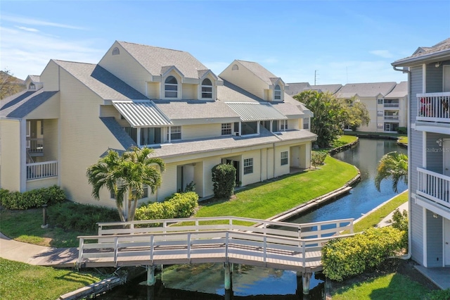 back of property with a residential view, a water view, and a yard