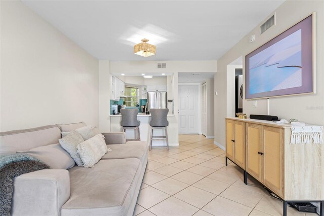 living room featuring light tile patterned floors, baseboards, and visible vents