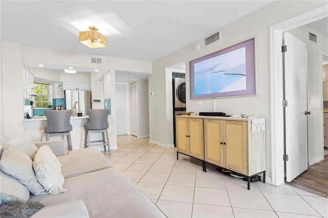 living room with visible vents, light tile patterned flooring, and stacked washer and clothes dryer