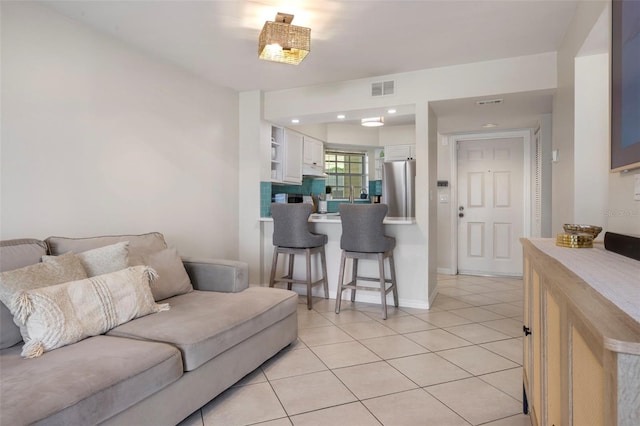 living room with visible vents, baseboards, and light tile patterned floors