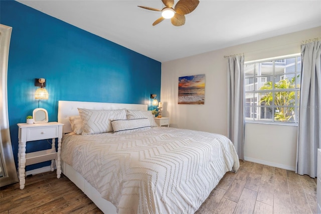 bedroom featuring ceiling fan, baseboards, and wood finished floors