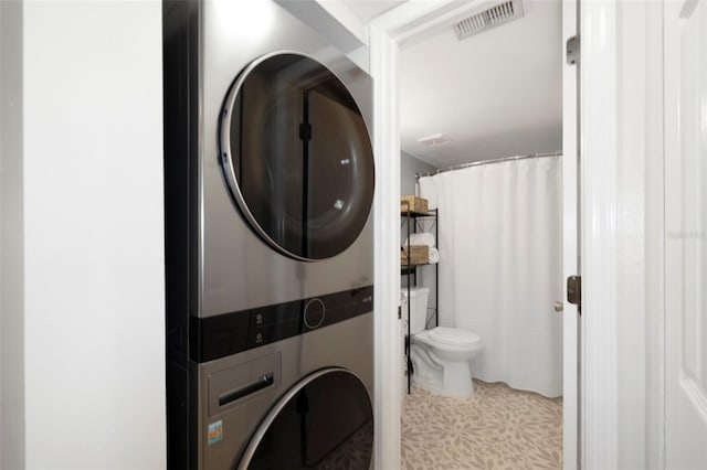 full bathroom featuring toilet, stacked washer / dryer, and visible vents