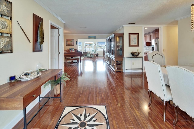 corridor featuring a textured ceiling, dark wood-type flooring, and ornamental molding