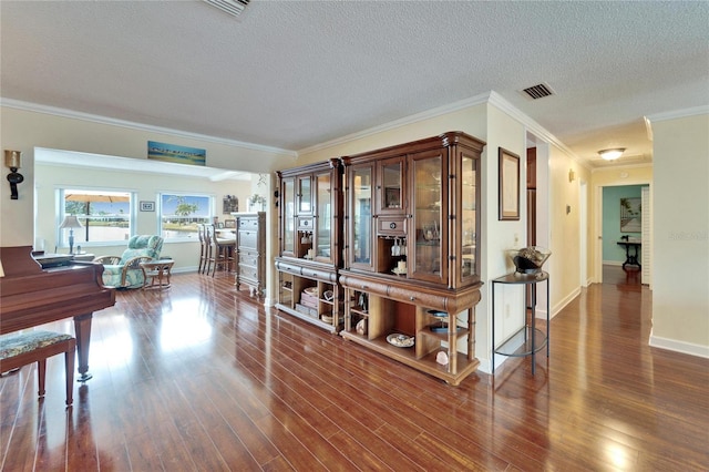 hall with visible vents, a textured ceiling, wood finished floors, and crown molding