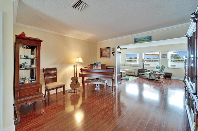 living area featuring crown molding, wood finished floors, visible vents, and a textured ceiling