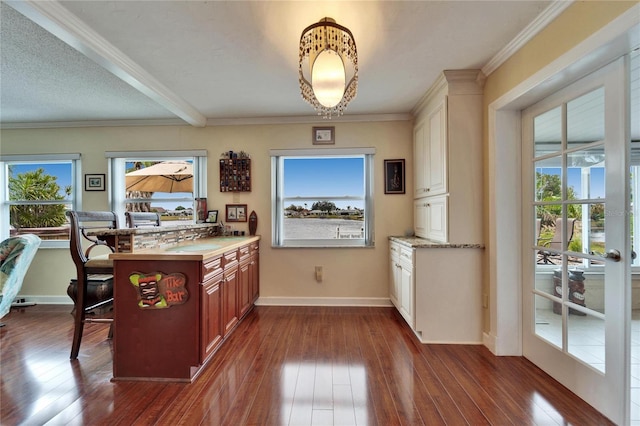 kitchen featuring a breakfast bar area, baseboards, dark wood-type flooring, light countertops, and crown molding