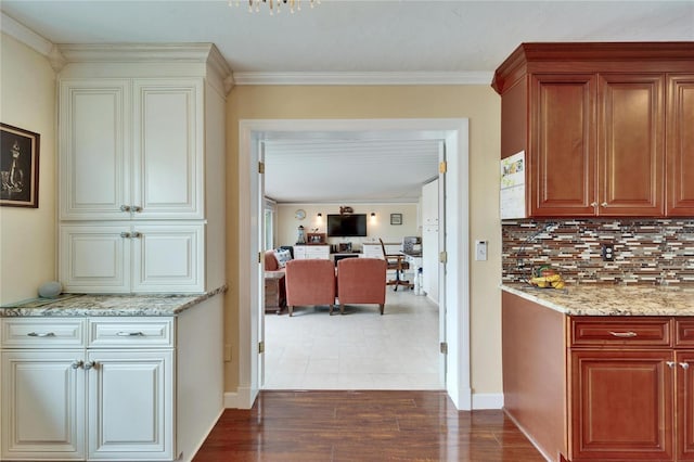 kitchen with wood finished floors, light stone countertops, baseboards, crown molding, and tasteful backsplash