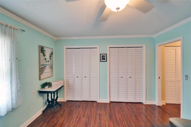 unfurnished bedroom with baseboards, multiple closets, ornamental molding, wood finished floors, and a textured ceiling