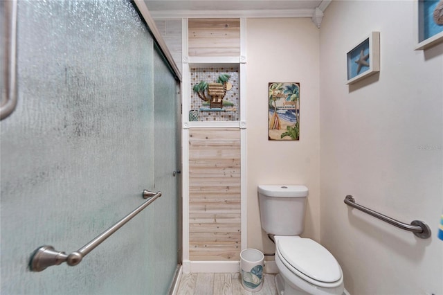 full bathroom with wood finished floors, baseboards, ornamental molding, a shower stall, and toilet