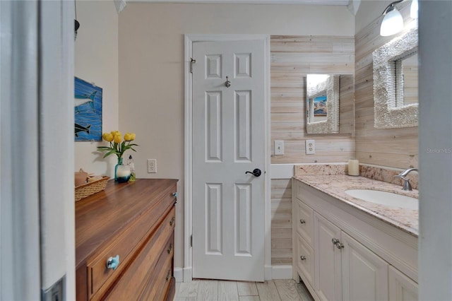 bathroom with wooden walls, wood finished floors, and vanity