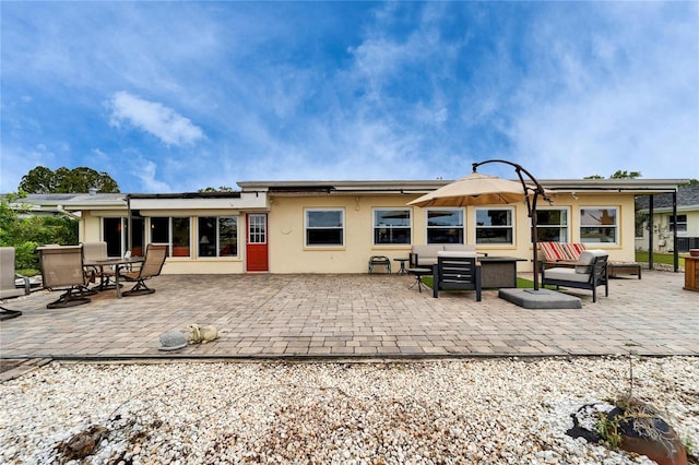 back of property with stucco siding, a patio, and an outdoor hangout area