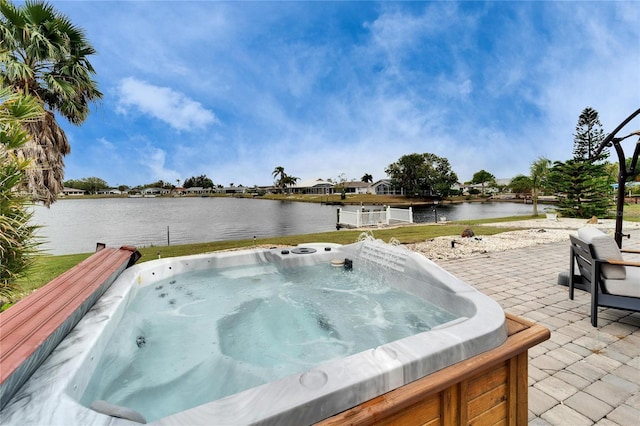 view of pool featuring a hot tub, a patio, and a water view